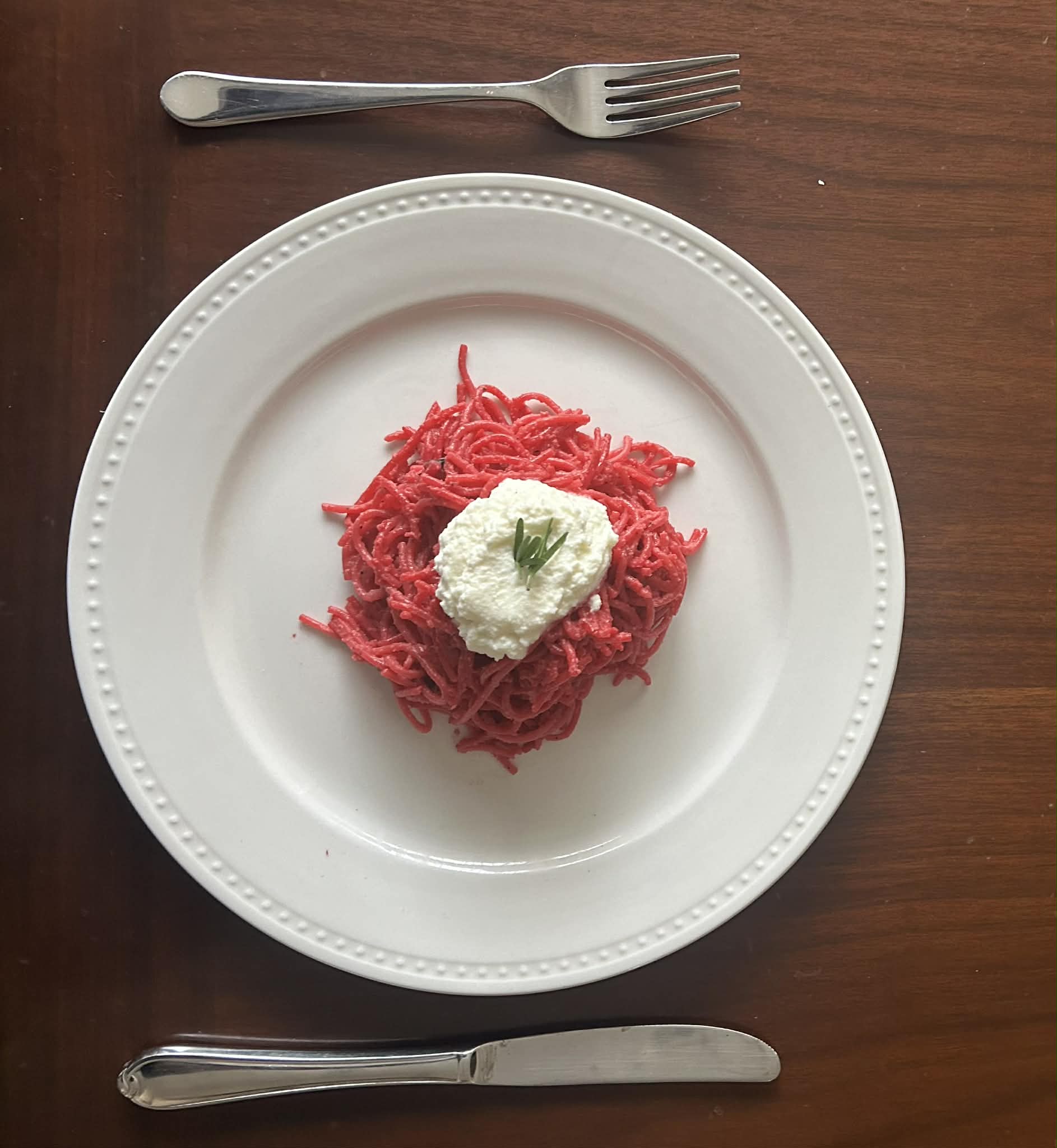 Beet pasta topped with whipped burrata and rosemary