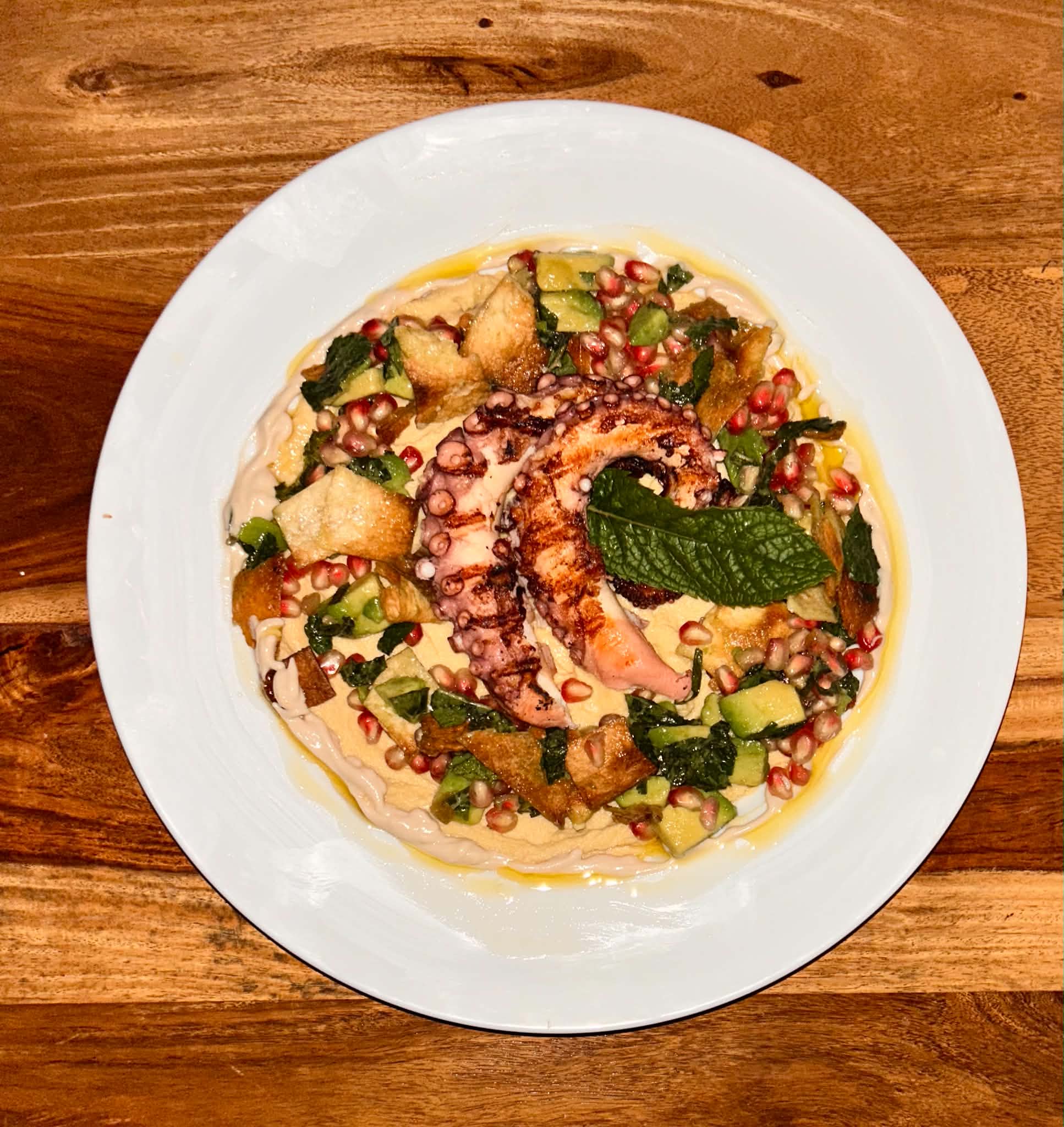 Grilled octopus over hummus with fattoush salad and pomegranate